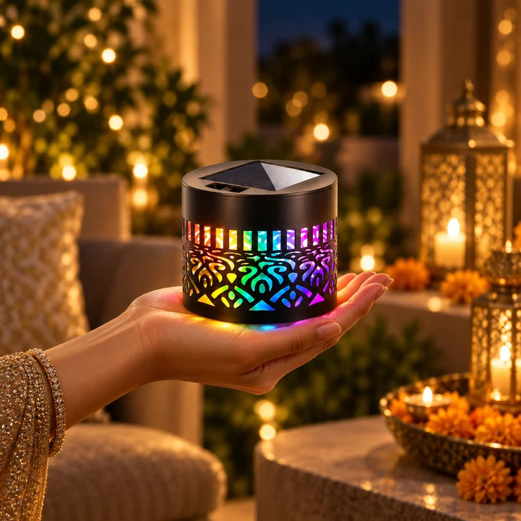 Compact black solar mandala light resting in a hand with multicolored glow